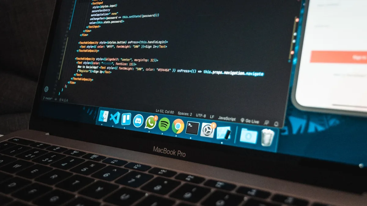 Un portátil muestra código de programación en un escritorio de trabajo