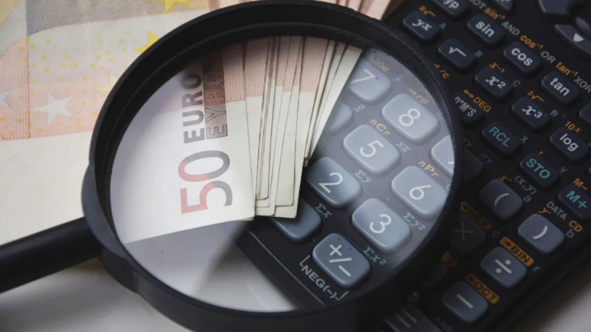 Billetes de cincuenta euros junto a una calculadora y una lupa sobre una mesa