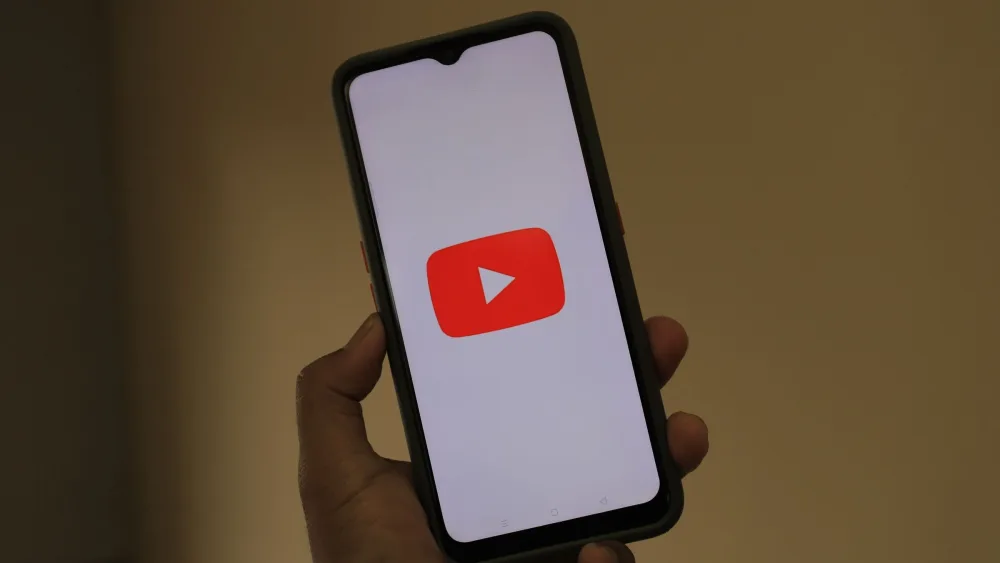 Una mano sostiene un móvil con el logotipo de una aplicación de vídeo en pantalla