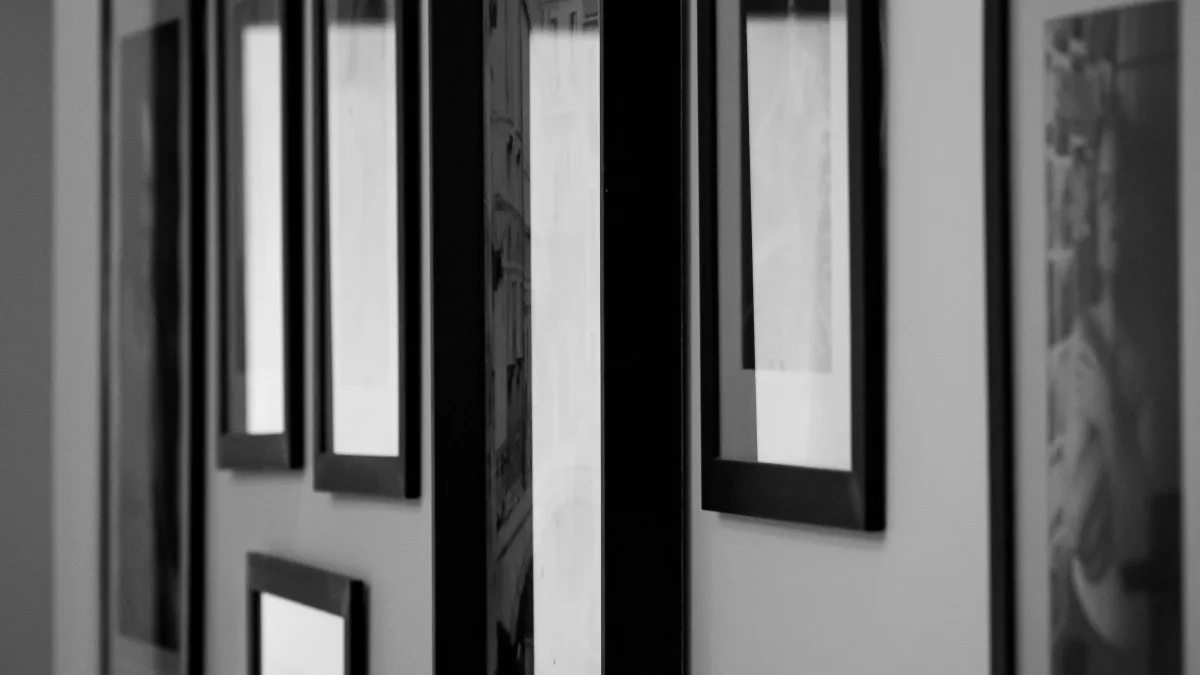 Cuadros enmarcados colgados en la pared de una galería, en blanco y negro