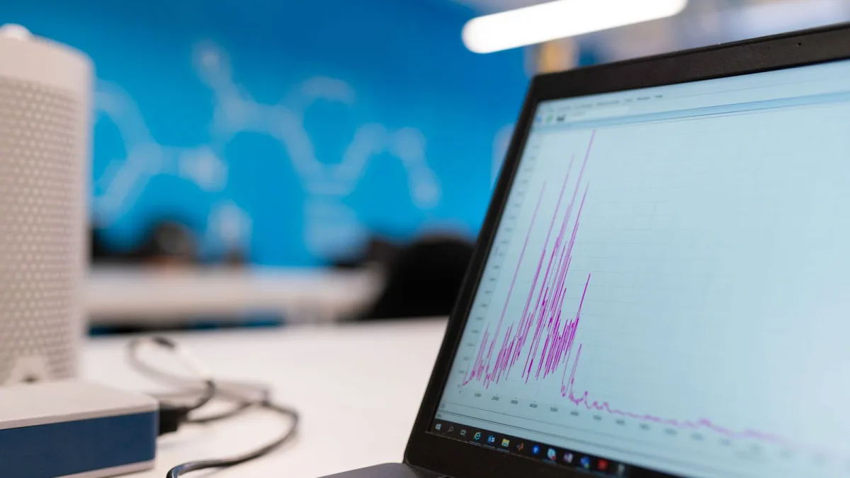 Un portátil muestra un panel de gráficas y analítica de datos sobre una mesa de oficina