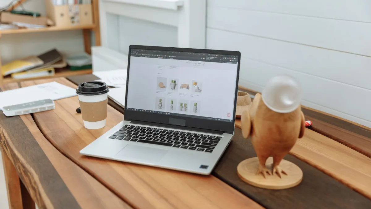 Un portátil muestra el diseño de una página web sobre una mesa de madera